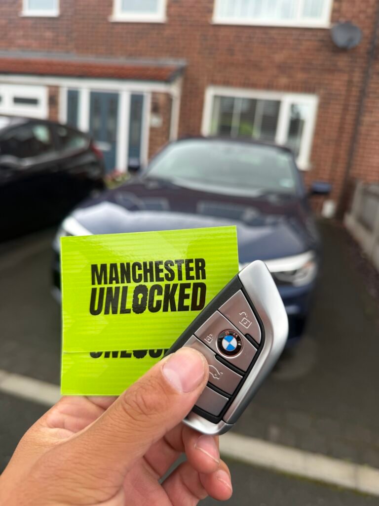 New original BMW key held in front of a 2020 BMW 5 Series in Sale, Trafford