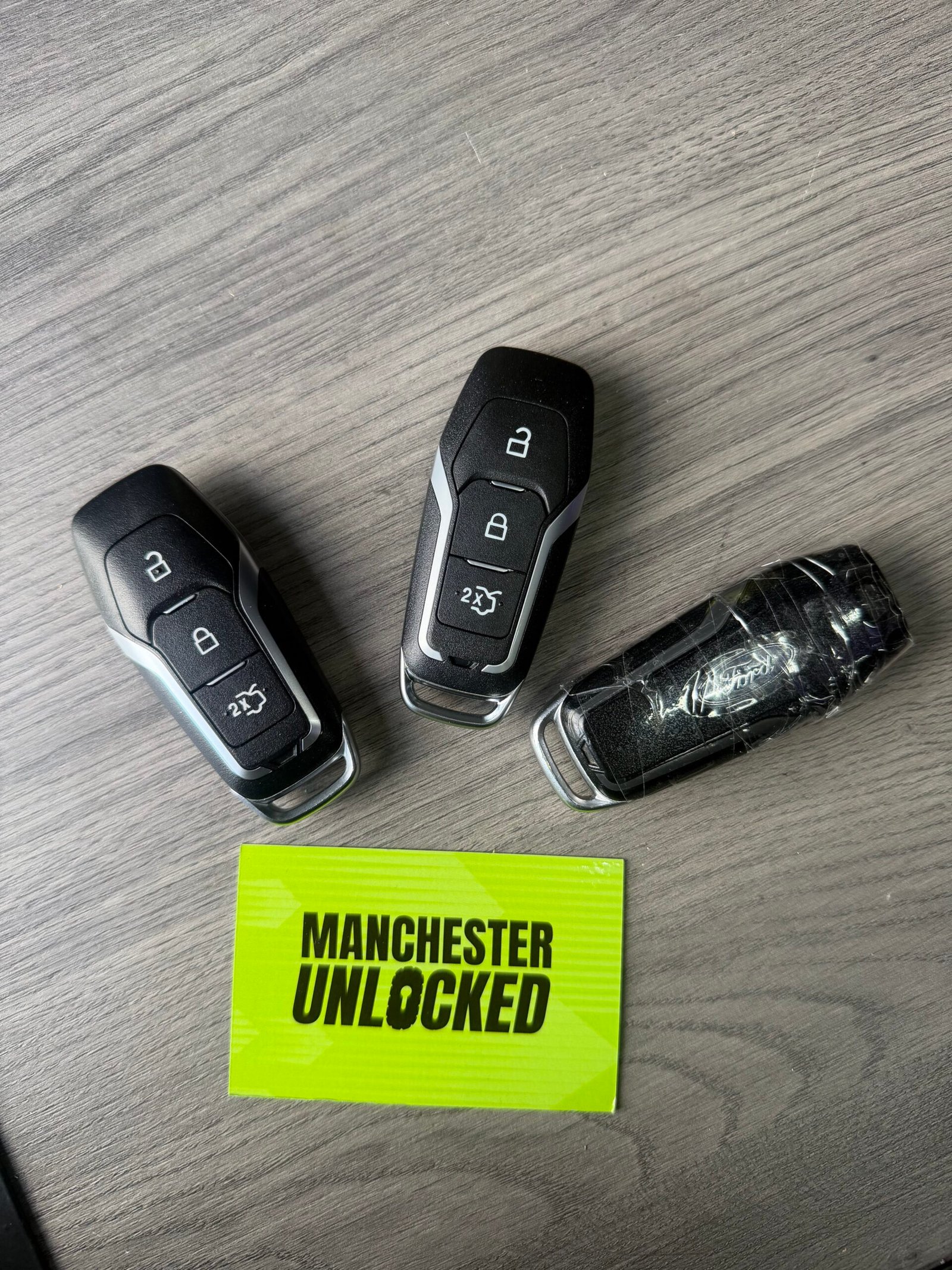Ford keys beside the old key held together with tape and a Manchester Unlocked card